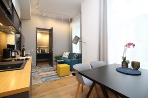 A modern living space with a kitchen, dining area, and a cozy seating area with a sofa and chairs.