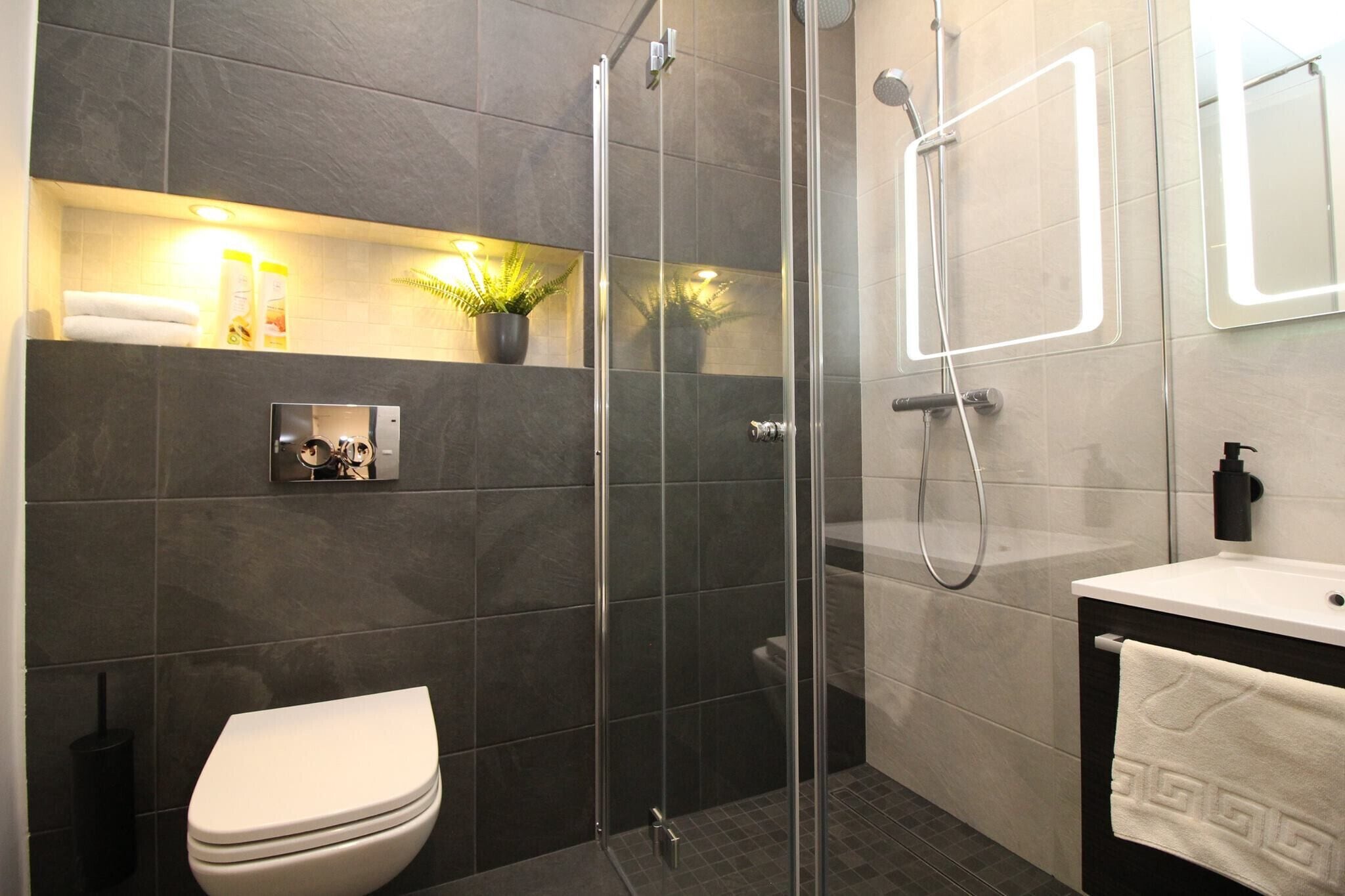 A modern bathroom with a glass-enclosed shower, a toilet, a sink, and a mirror.