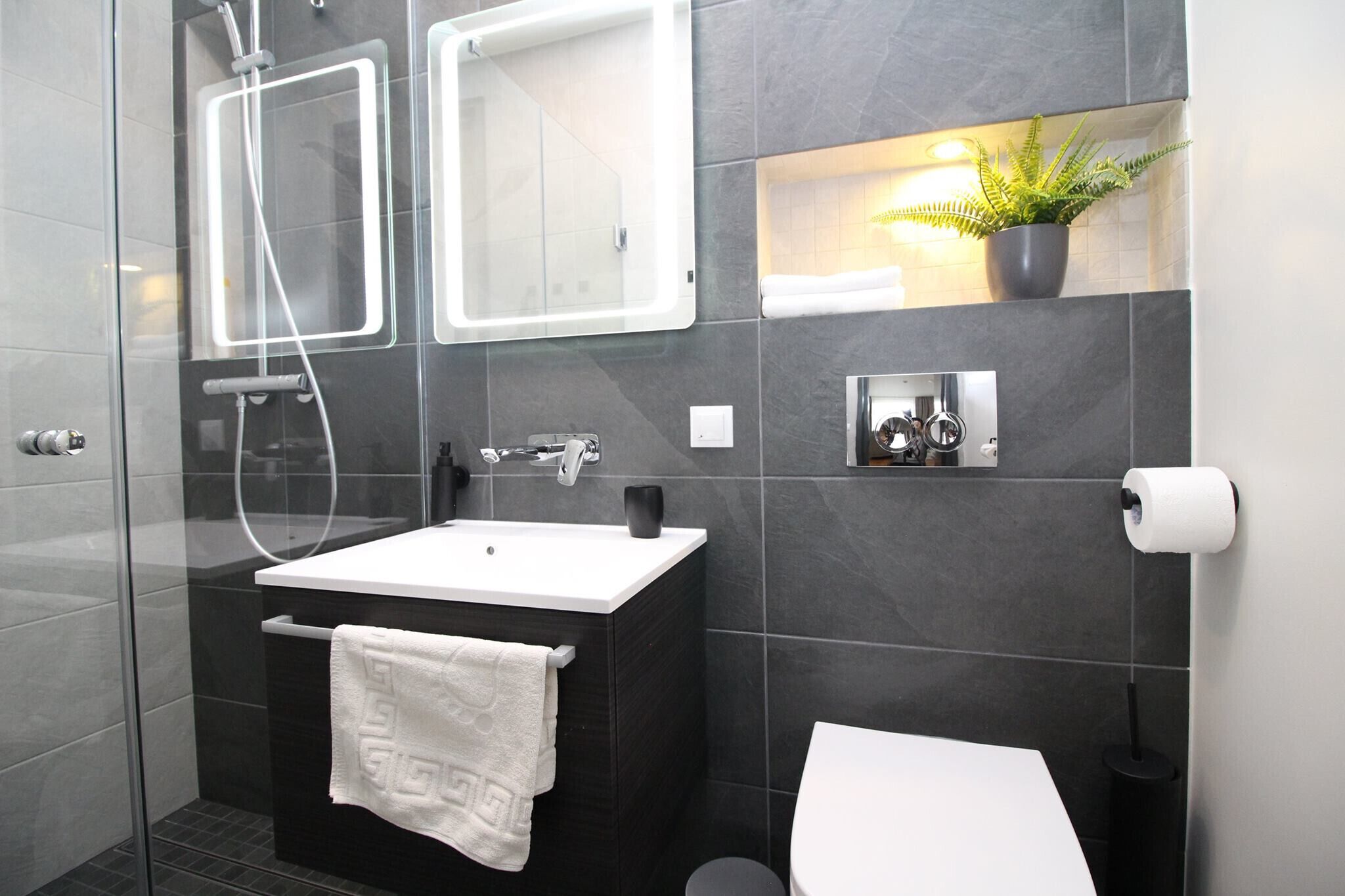 Une salle de bain moderne avec une douche à parois de verre, un lavabo blanc et des toilettes.