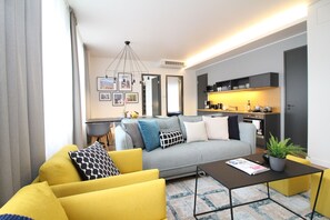 A modern living room with a sofa, yellow armchairs, a coffee table, and a kitchen area in the background. - Tallinn City Apartments Old Town Suites (Tallinn)