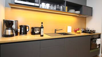 A modern kitchen with a microwave, coffee maker, wine bottle, and various kitchen utensils.