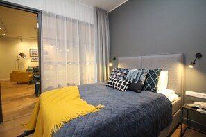 Ein modernes Schlafzimmer mit einem großen Bett, einem Nachttisch, einer Lampe und Blick auf den Raum.