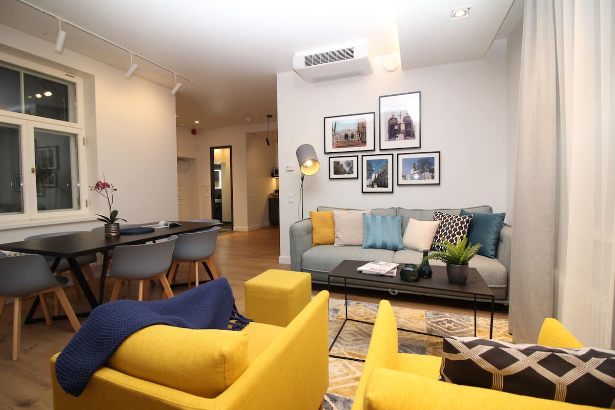 Uma sala de estar moderna com um sofá, cadeiras, uma mesa de centro e um espaço de jantar com cadeiras e uma mesa.