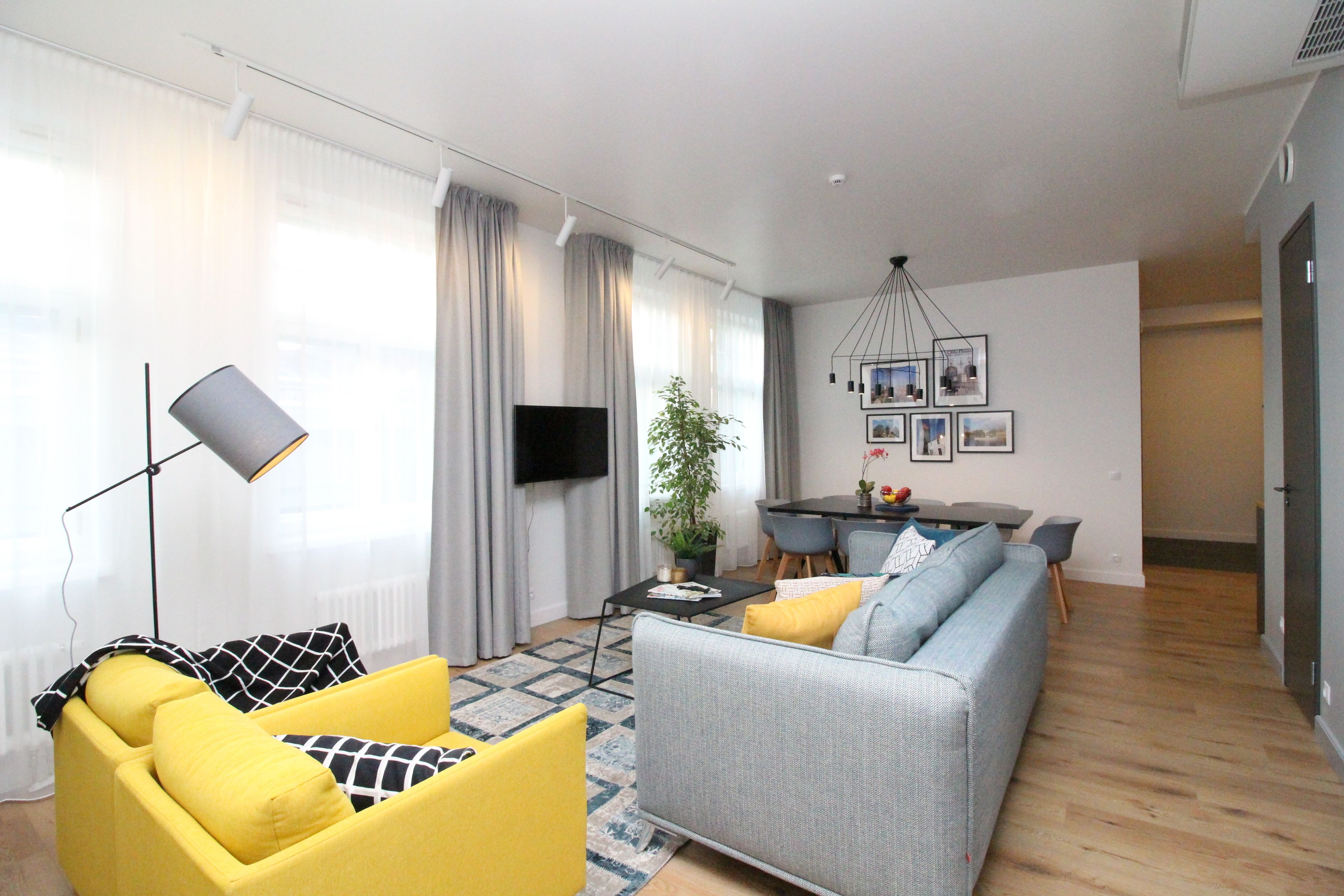 Un salon moderne comprenant un canapé, un fauteuil et un coin repas avec une table et des chaises.