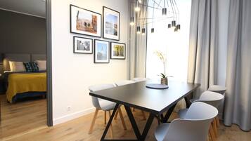 A modern dining area with a long table, six chairs, and a chandelier.