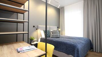 Un dormitorio moderno con cama, escritorio y silla.