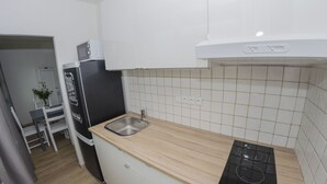 Een moderne keuken met witte kasten, een houten aanrecht, een zwarte kookplaat en een spoelbak.