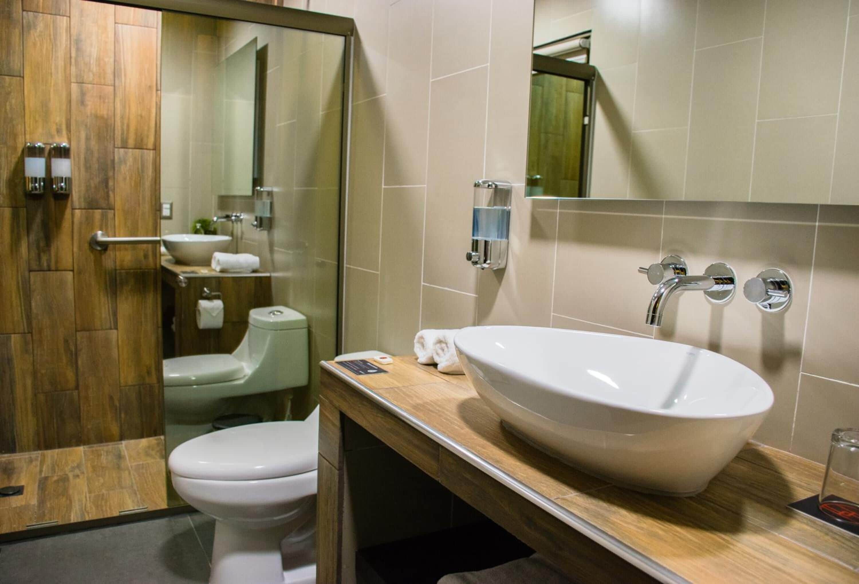 A modern bathroom with a large white sink, a toilet, and a mirror.