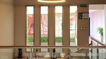 A modern interior with a staircase, glass railings, and large windows.