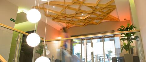Un interior moderno con diseño de techo de madera, barandillas de cristal y plantas de interior.
