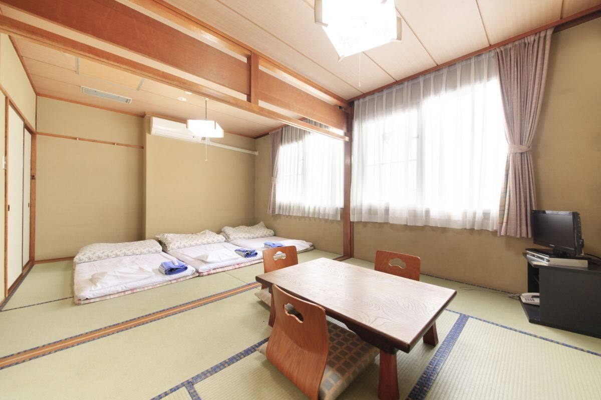 A traditional Japanese room with tatami mats, a low wooden table, and futon beds.