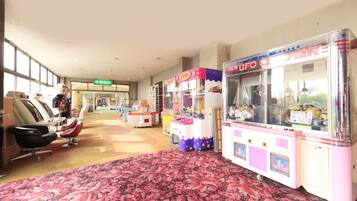 A hotel lobby with a floral carpet, a salon area with chairs, and claw machines.