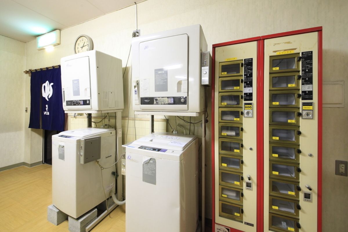 A room with two white refrigerators, a clock on the wall, and a filing cabinet with multiple drawers.