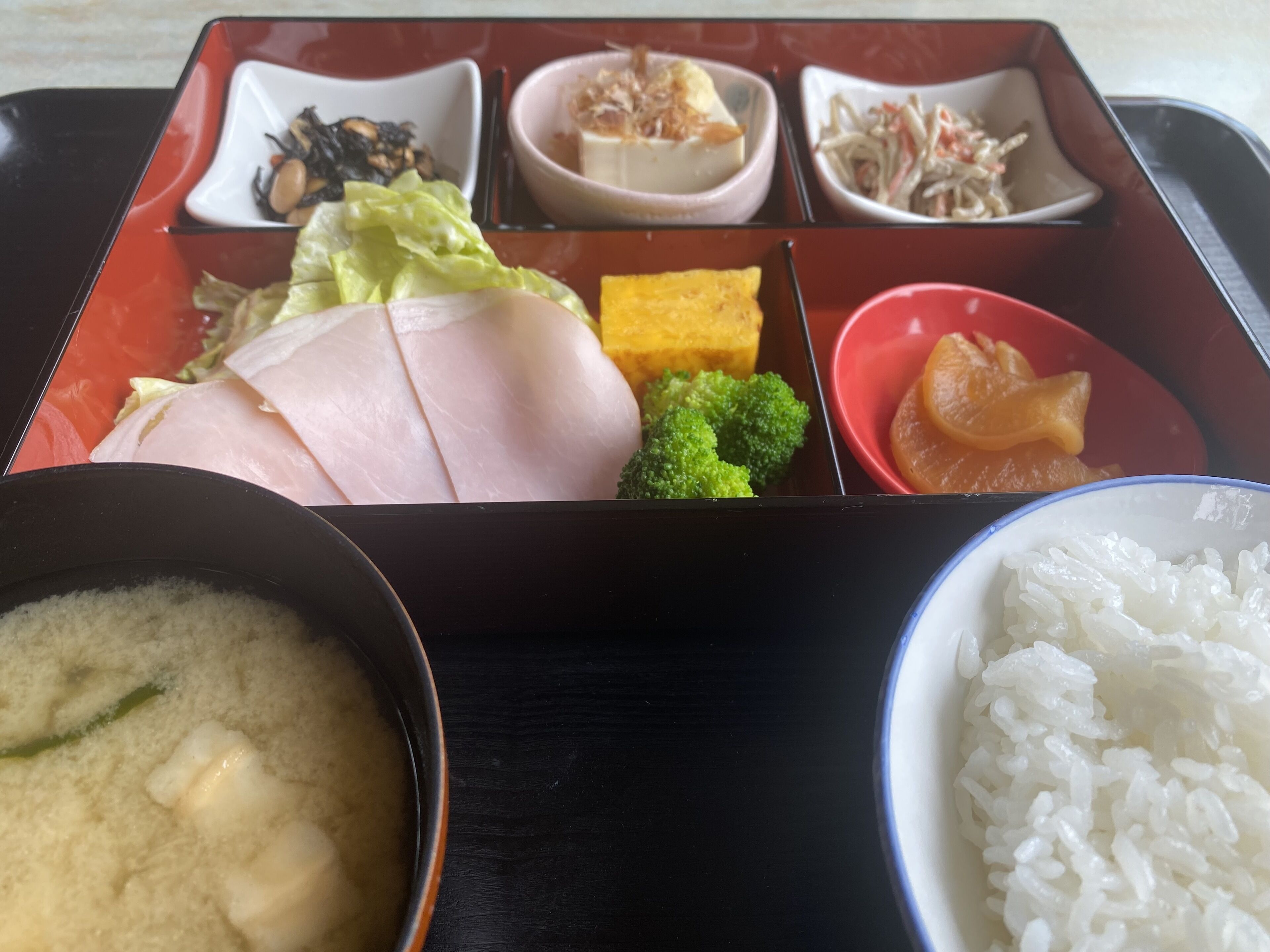 A bento box with various food items including fish, vegetables, and rice.