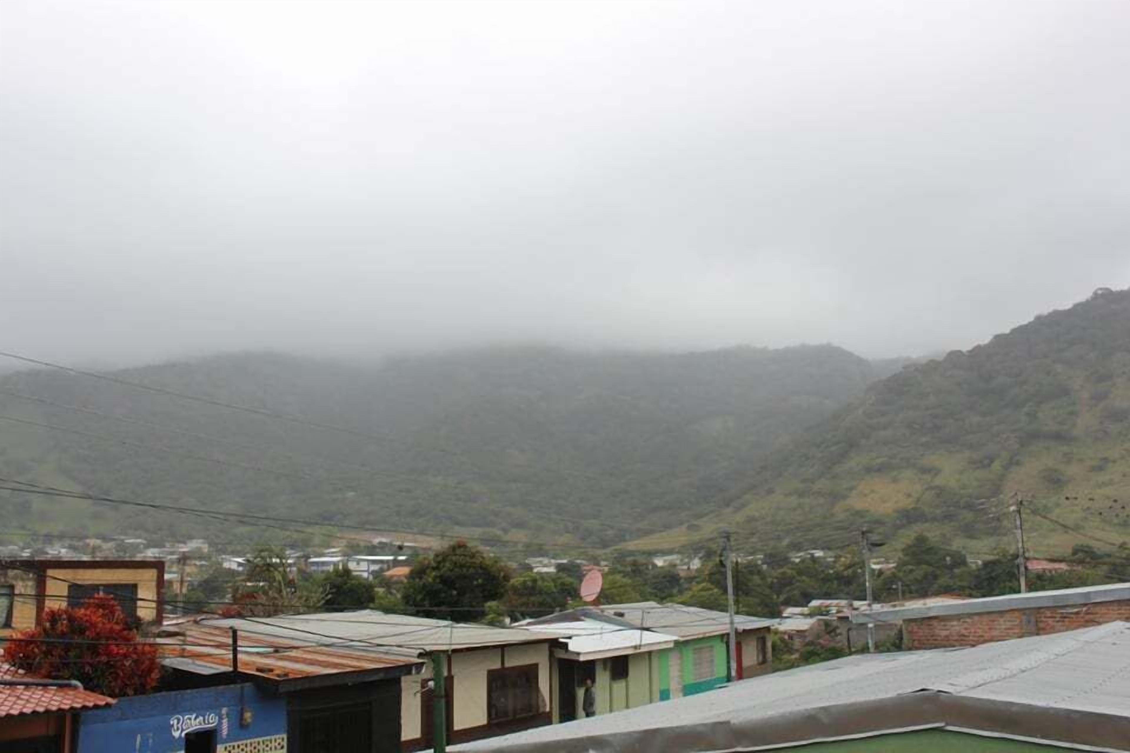 A residential area with houses and a hilly landscape in the background.