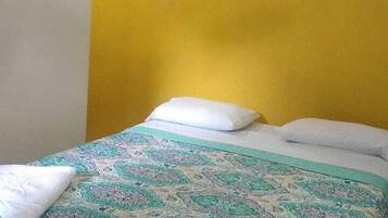 Een slaapkamer met een bed, een plafondventilator en een lijst met een afbeelding aan de muur.