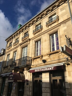 A historic building with a restaurant on the ground floor, multiple balconies, and a sign indicating it houses a hotel and a bar. - Hotel du Commerce (Semur-en-Auxois)