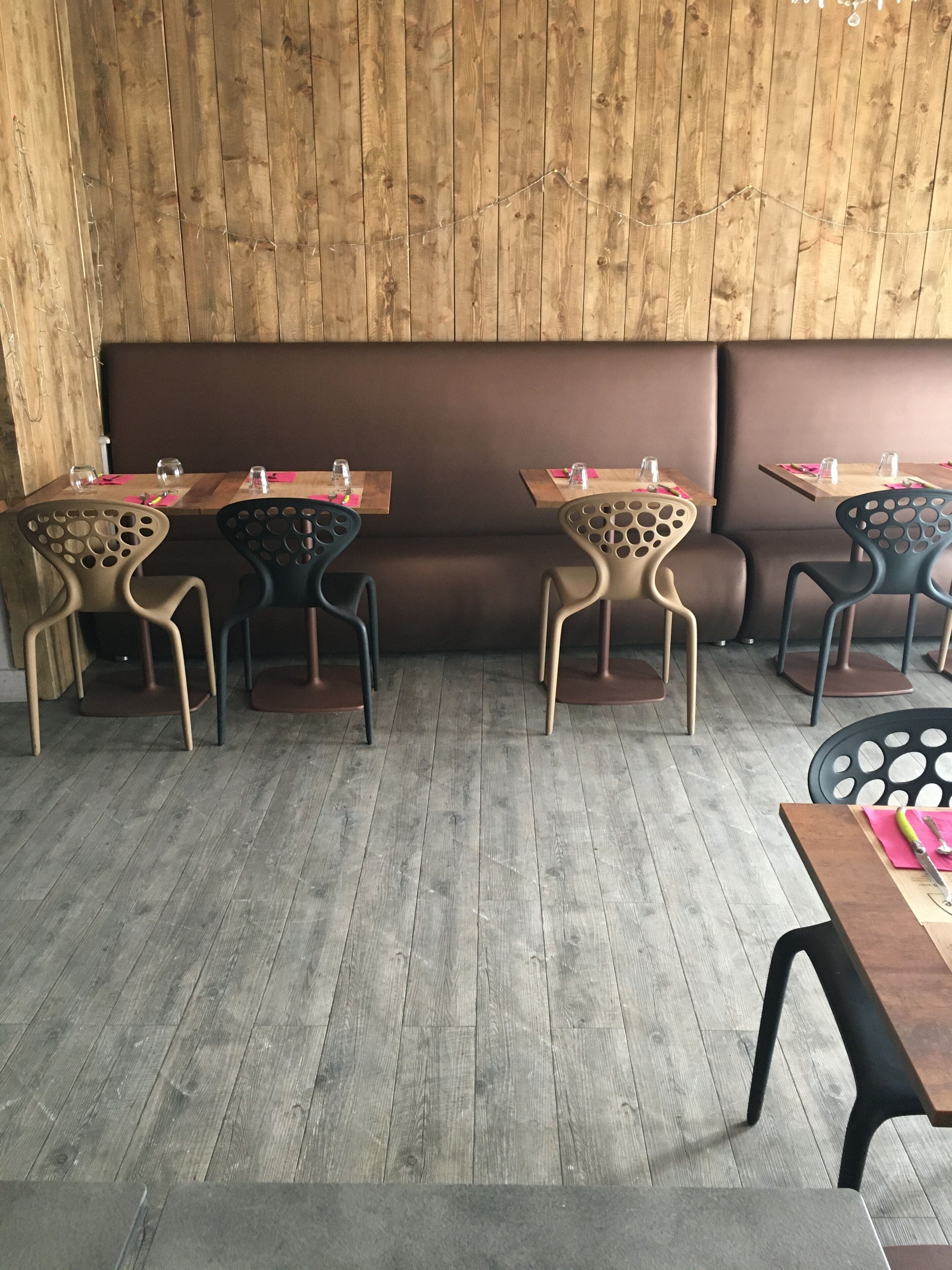 A restaurant with wooden walls, a central bench, and tables with chairs.