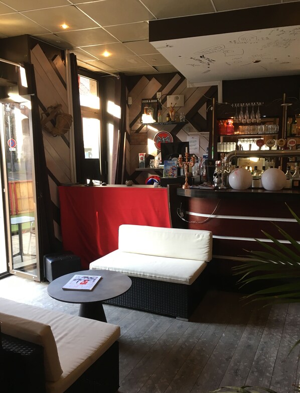 A bar area with a red booth, a bar counter, and various bottles and glasses.