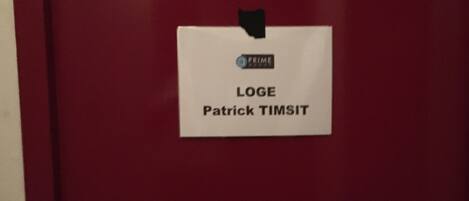 A red door with a white sign that reads "LOGE Patrick TIMSIT".