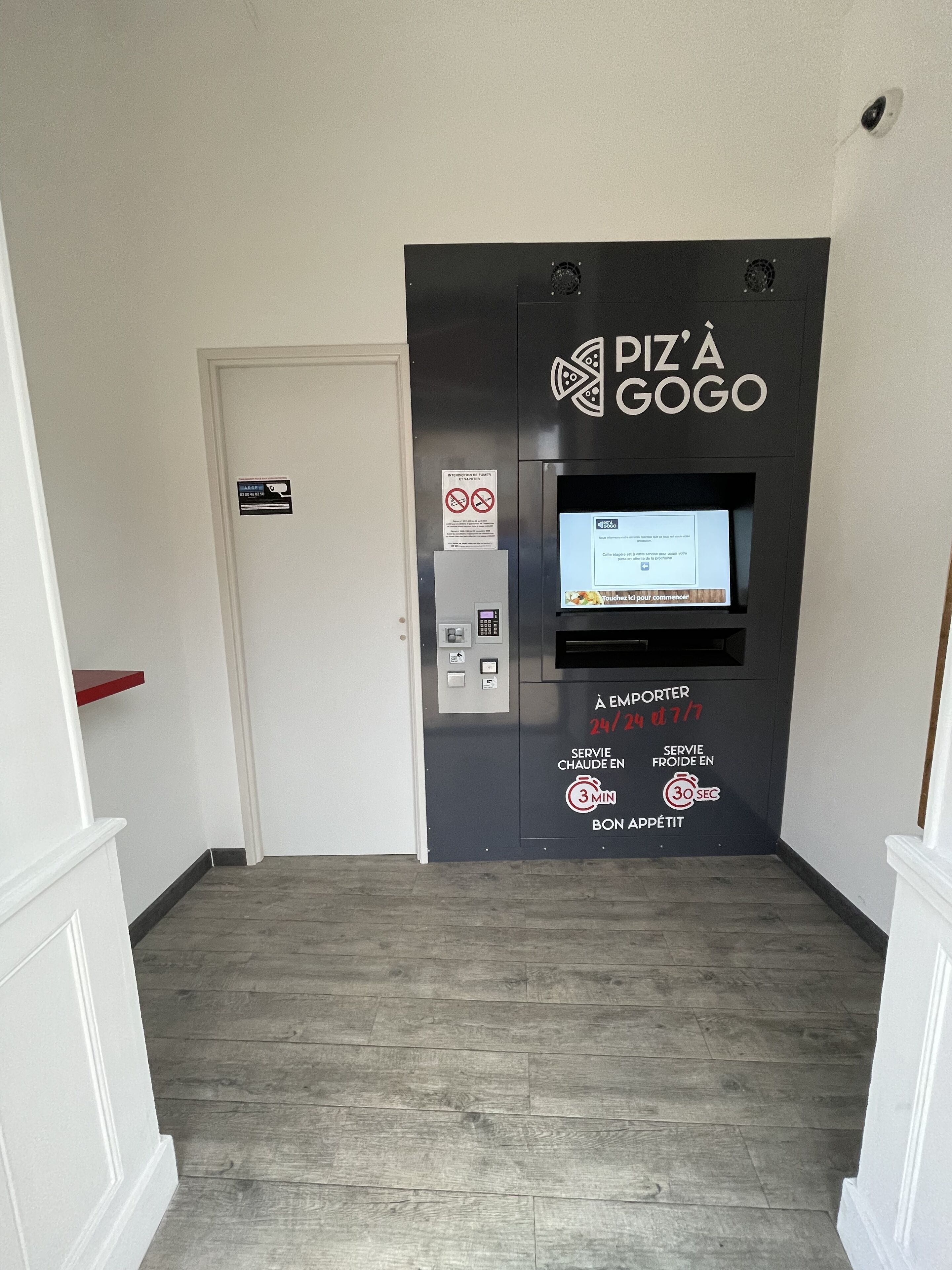 Un quiosco de pizza autoservicio con pantalla digital, horario de atención y opciones de temperatura.