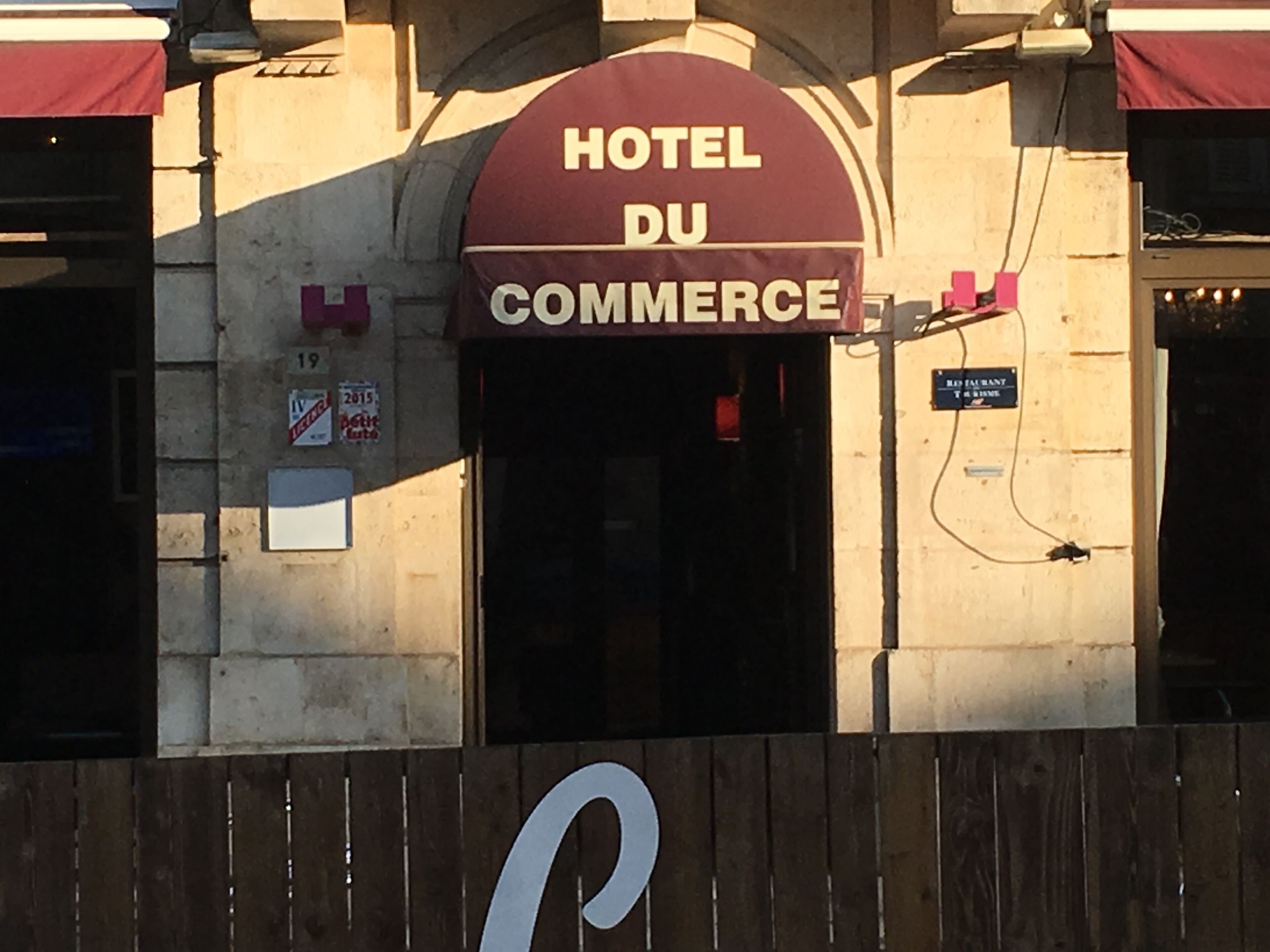 A building with a sign that reads "HOTEL DU COMMERCE."