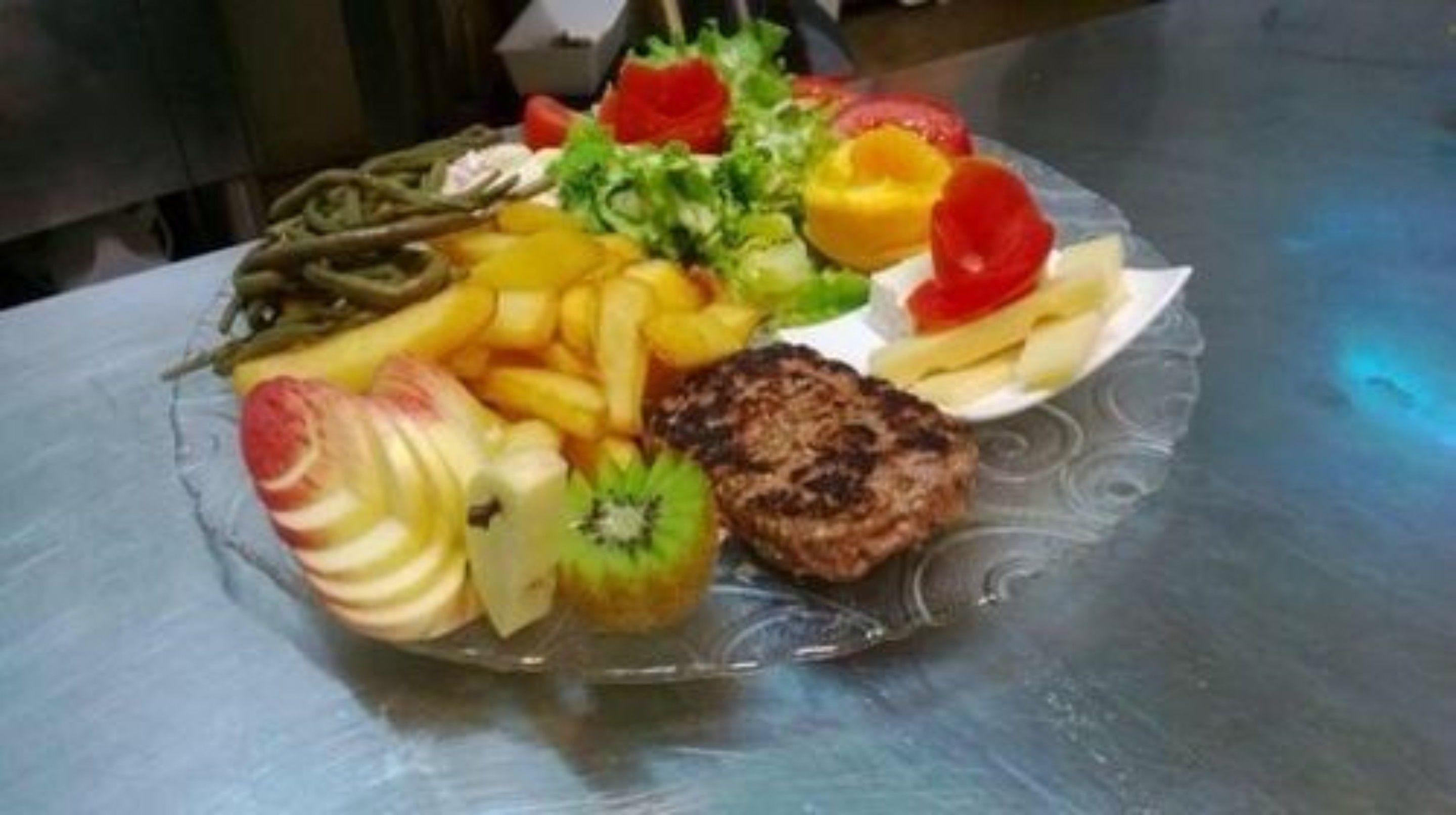 A plate with a steak, fries, and various fruits.