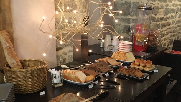 Un buffet proposant une variété de plats, un panier de pain et un distributeur de boissons.