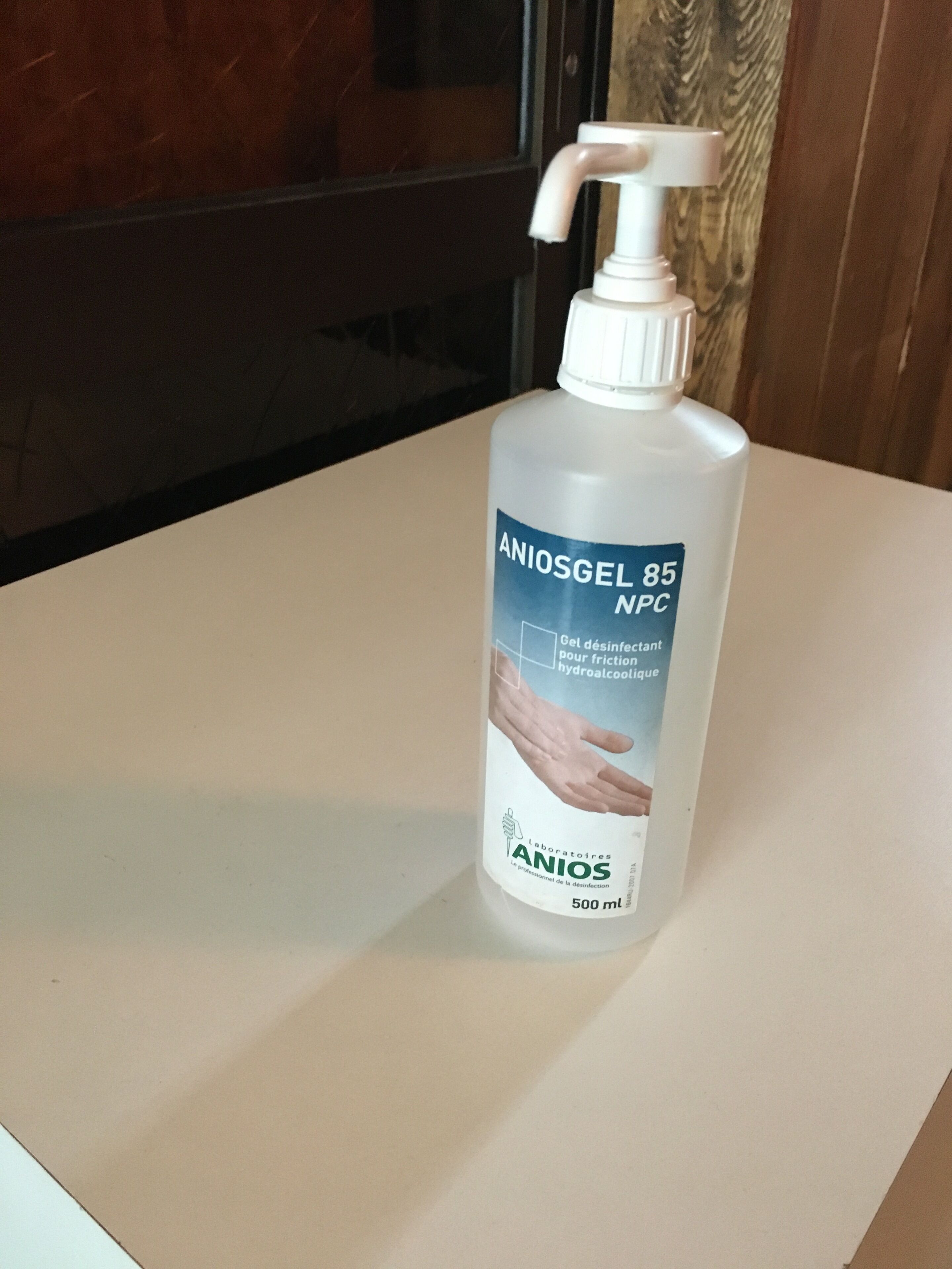 A bottle of Aniosgel 85 MNC hand sanitizer on a white surface.