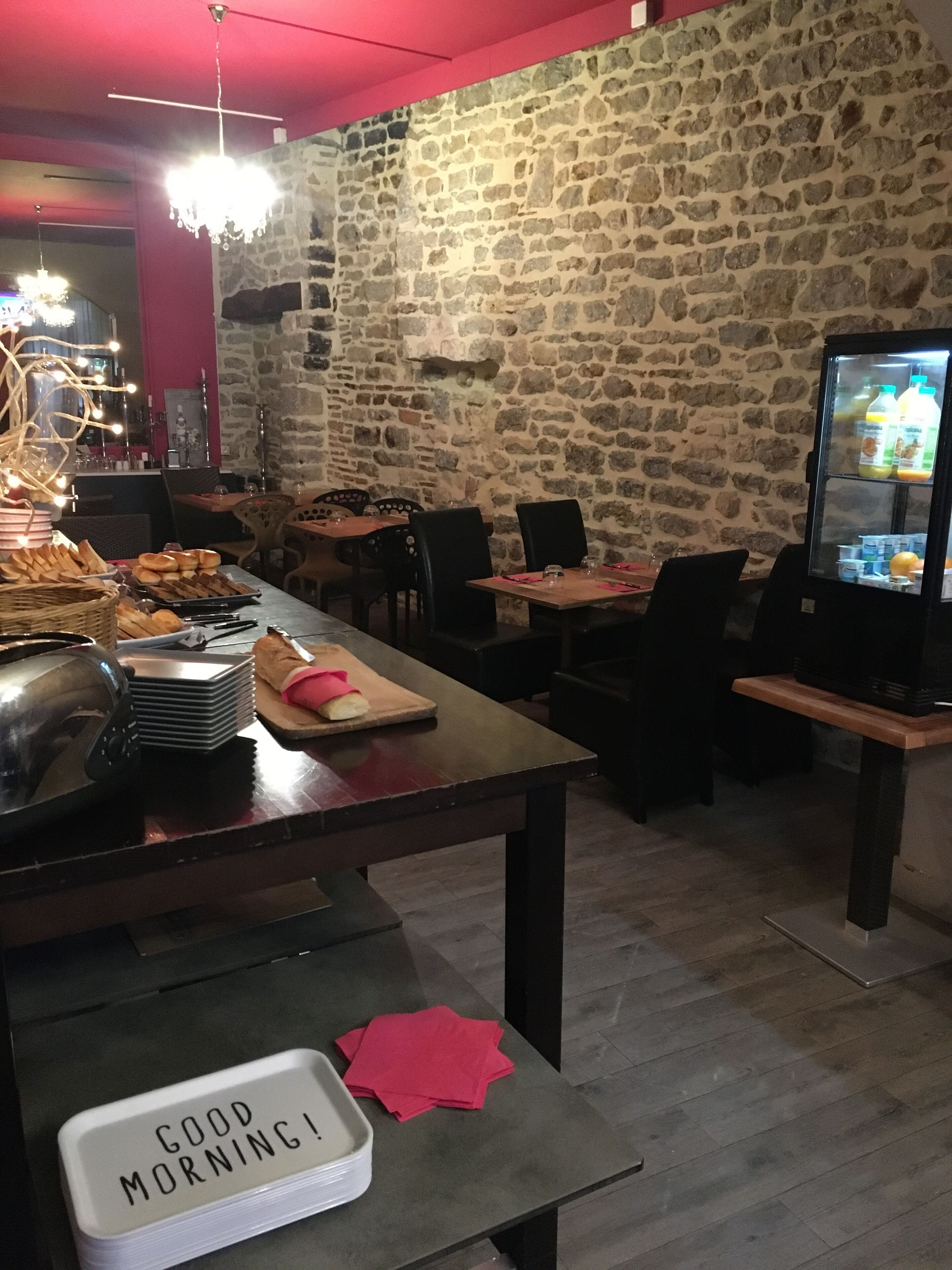 Un restaurant aux murs de pierre, aux tables en bois et dont le réfrigérateur est rempli de boissons.