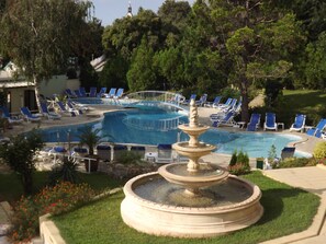 A swimming pool with a fountain, surrounded by lounge chairs and greenery. - Silver Hotel (Varna)