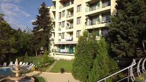 Ein mehrstöckiges Hotel mit Balkonen, einem Schwimmbad und einem gepflegten Garten.