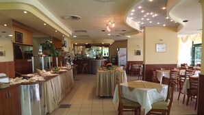 Ein Restaurant mit mehreren Tischen, Stühlen, einer Bar und einer Küche im Hintergrund.