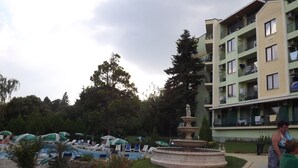 Ein Innenhof mit Brunnen, Liegestühlen und einem Pool.