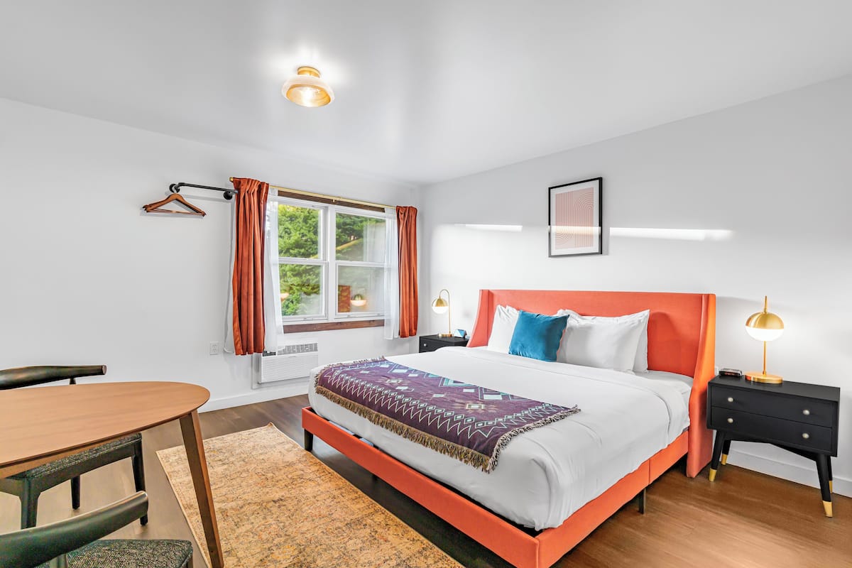 Een moderne slaapkamer met een bed, nachtkastjes, een bureau en een raam met gordijnen.