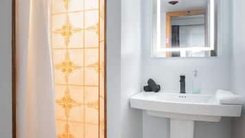 A bathroom with a shower, a sink, and a mirror.
