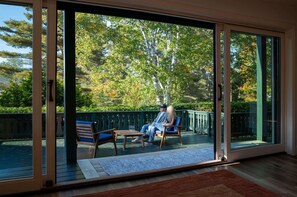 Une pièce dotée d’une porte-fenêtre coulissante qui donne sur un espace extérieur aménagé avec deux chaises et une table.