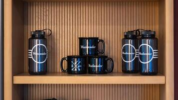 Un estante de madera con varios artículos de la marca 'Weekender', incluyendo tazas, una bolsa y una almohada.