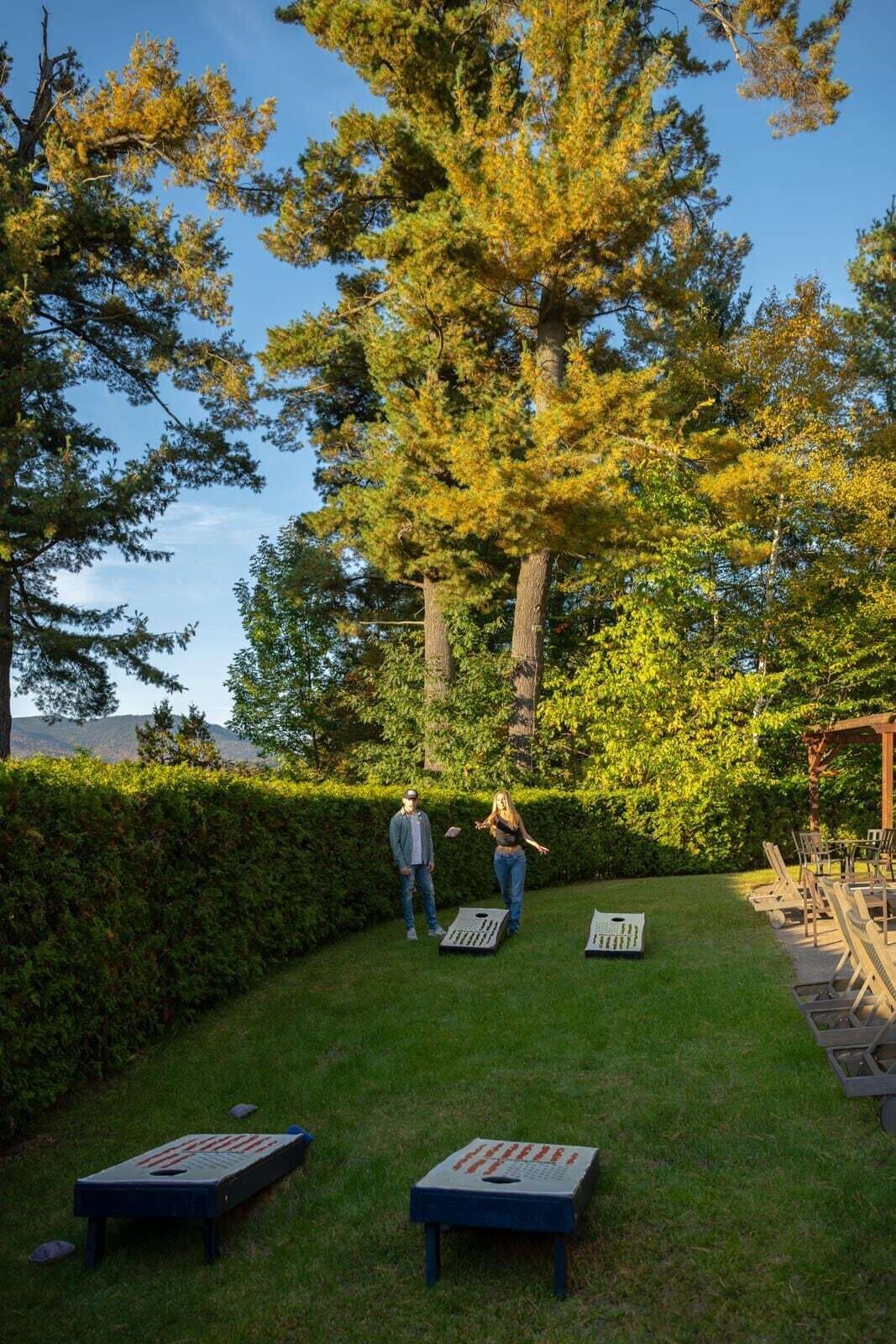 A grassy outdoor area with two shuffleboard tables and a pergola with seating.