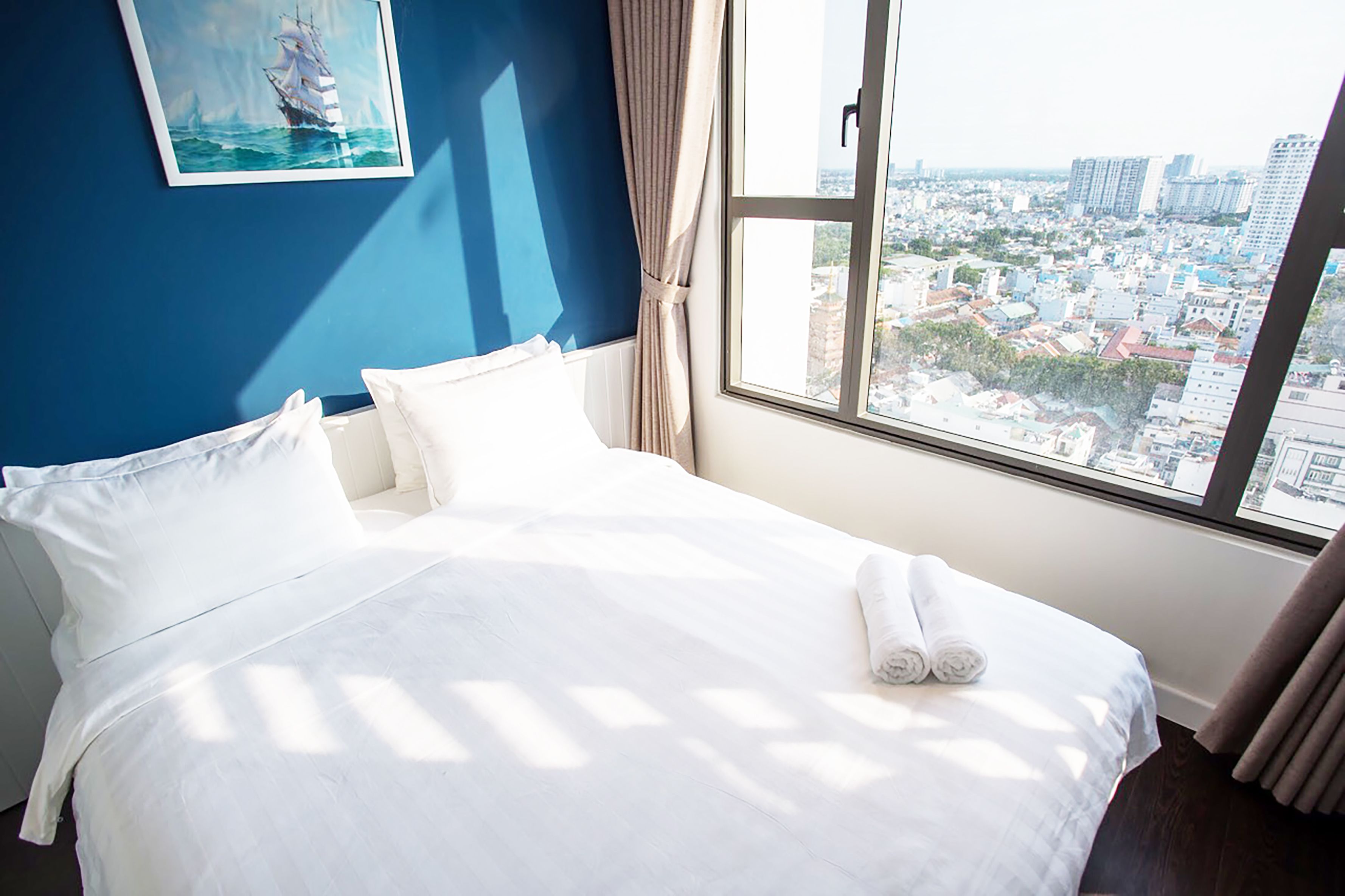 Hotelkamer met een groot bed, uitzicht op een stadsbeeld door een raam en een schilderij aan de muur.