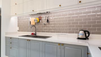 A modern kitchen with grey cabinets, a white countertop, and a tiled backsplash.
