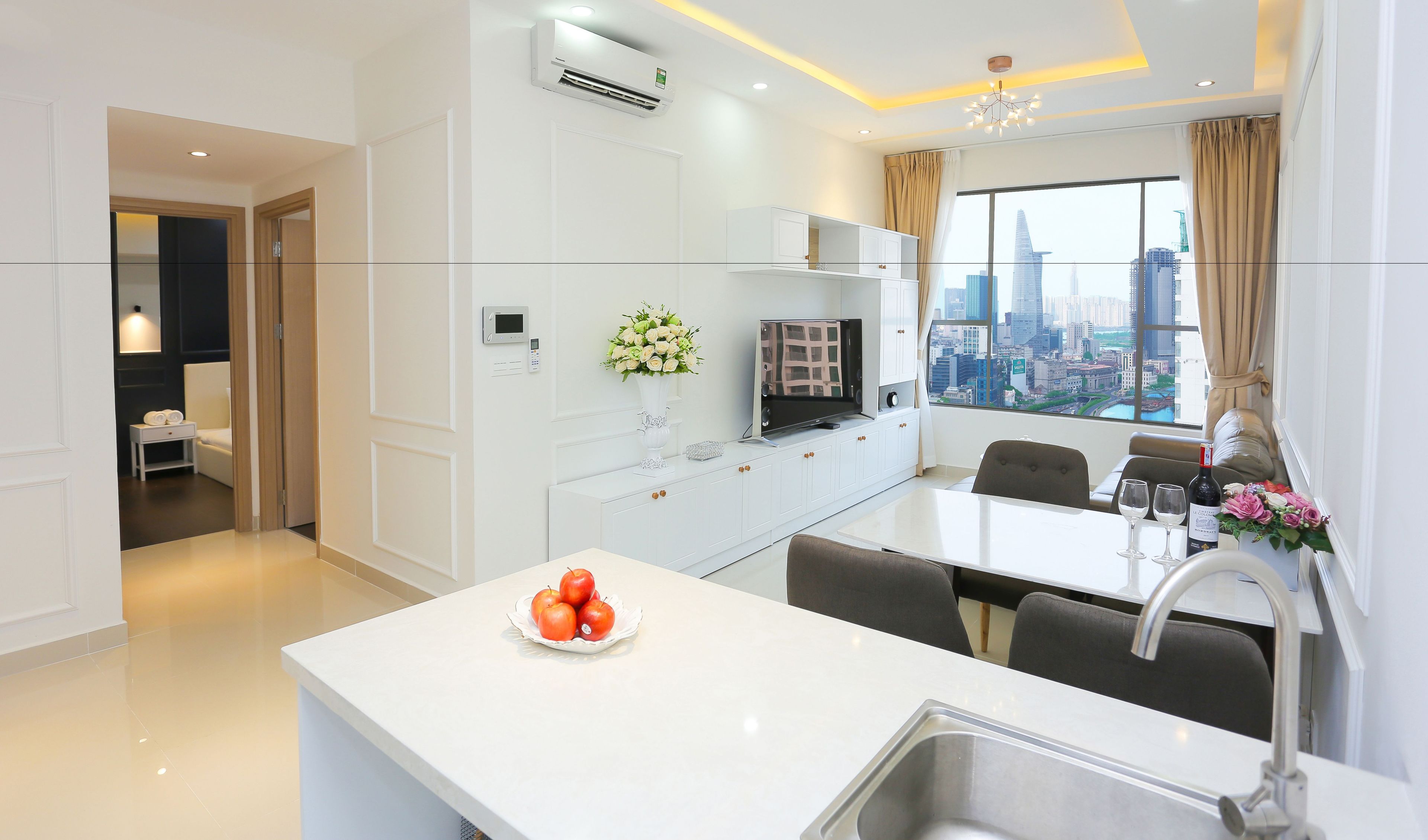 A modern kitchen with a dining area, a built-in oven, a microwave, and a large window with a city view.