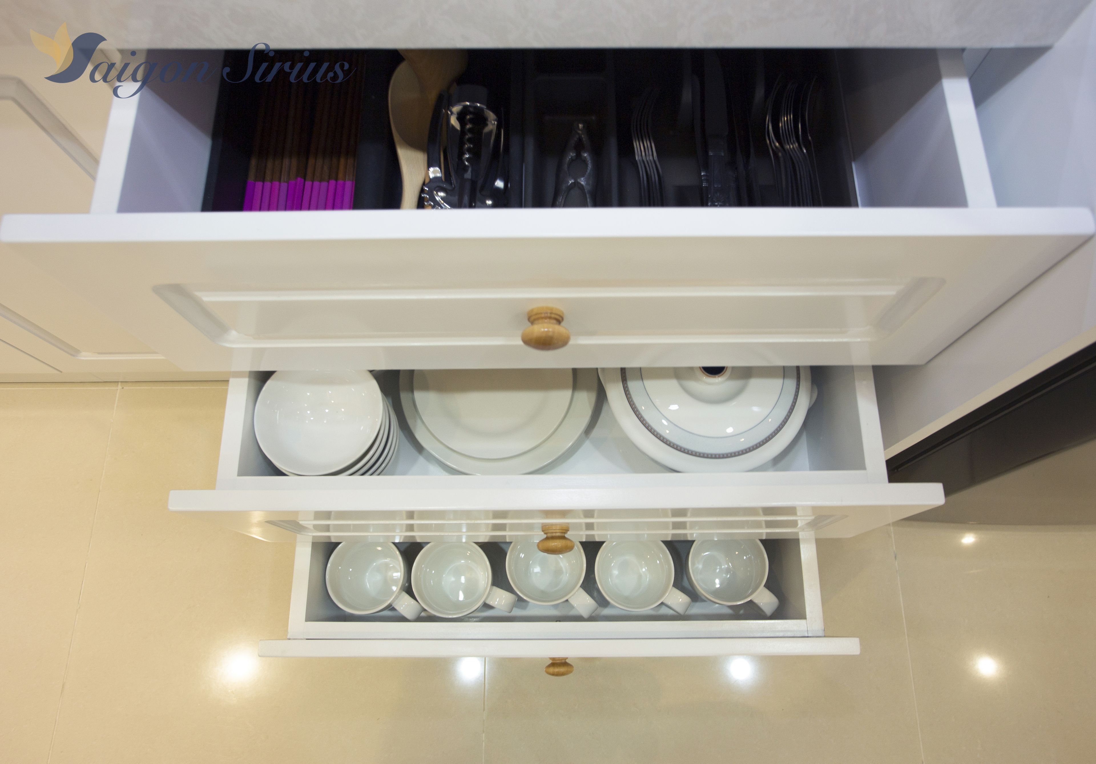 A kitchen cabinet with white shelves holding plates, bowls, and utensils.