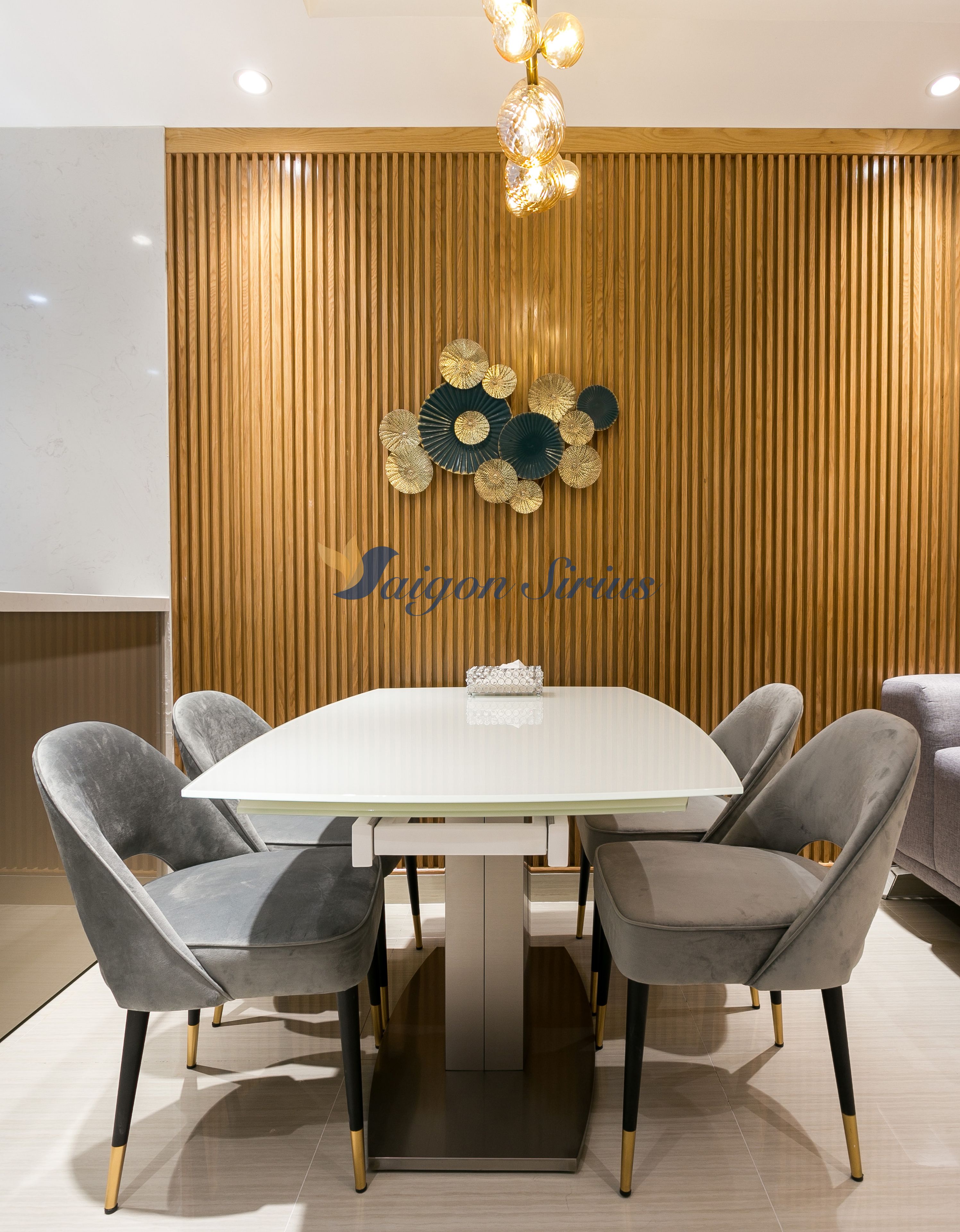 A modern dining area with a white table, grey upholstered chairs, and a decorative wall panel.