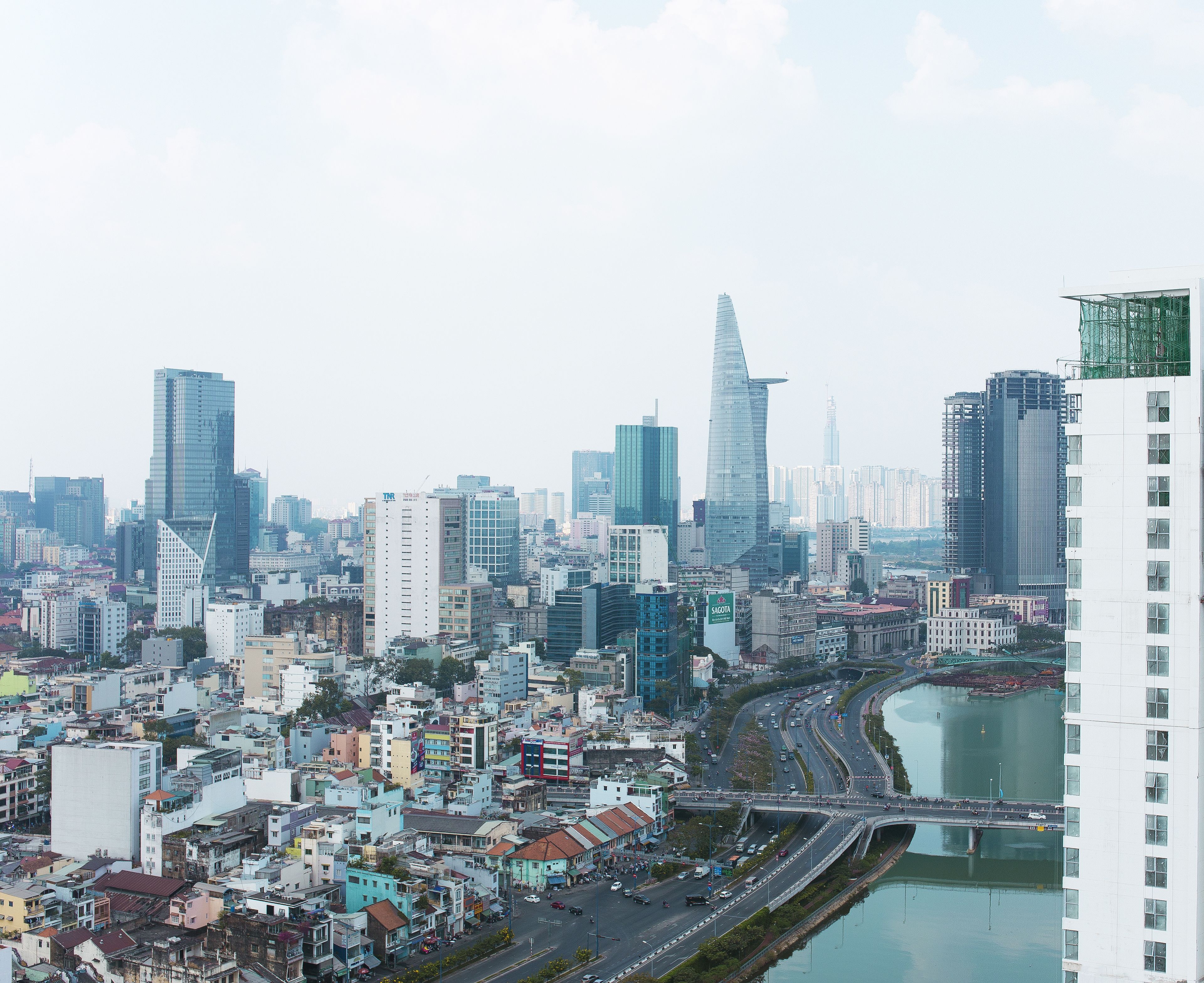 A cityscape with modern high-rise buildings, a river, and a bridge.
