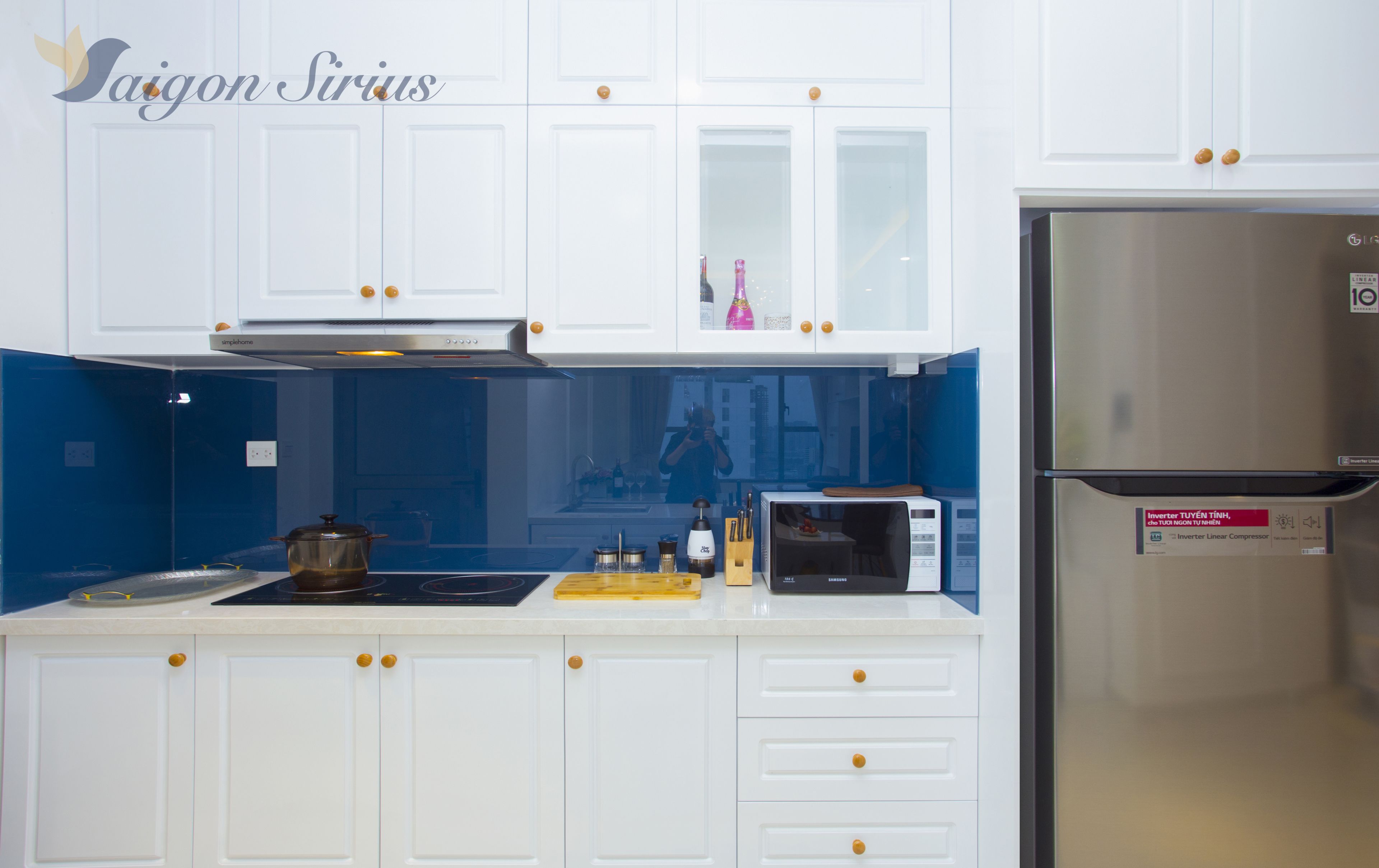 A modern kitchen with white cabinets, a stainless steel refrigerator, a microwave, and a gas stove.
