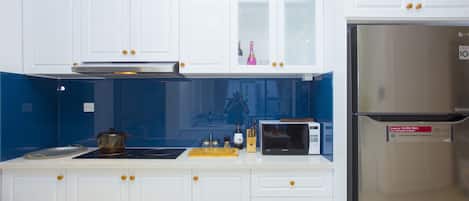 A modern kitchen with white cabinets, a stainless steel refrigerator, a microwave, and a gas stove.