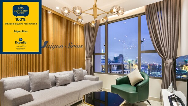 A modern living room with a grey sofa, a green armchair, and a black coffee table. A large window offers a city view. - Saigon Sirius (Ho Chi Minh City)