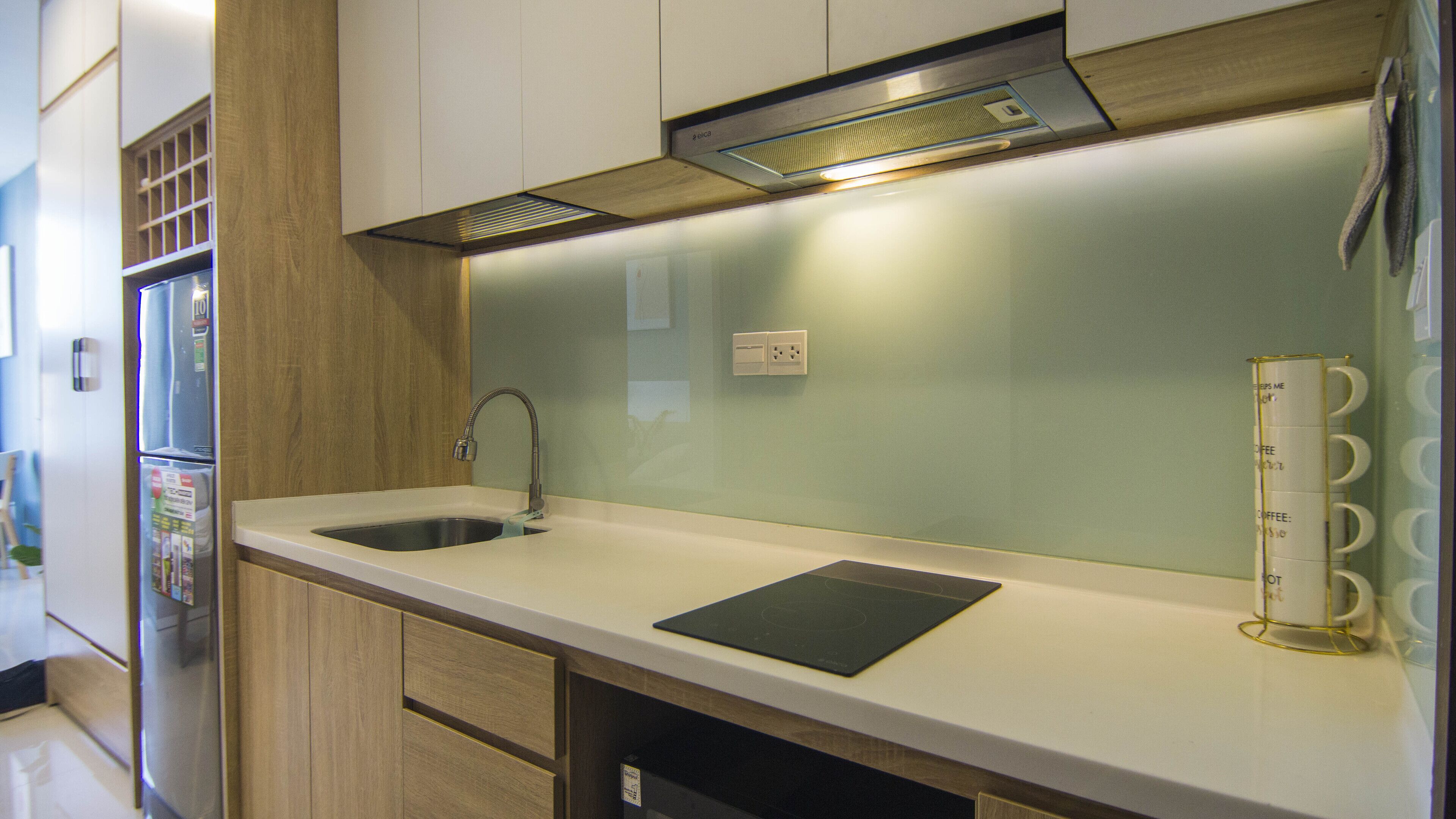 Een moderne keuken met een roestvrijstalen spoelbak, houten kasten, een inbouwafzuigkap en een koffiehoek.