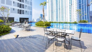 A modern hotel with a rooftop pool area, outdoor seating, and high-rise buildings in the background. - Saigon Sirius (Ho Chi Minh City)
